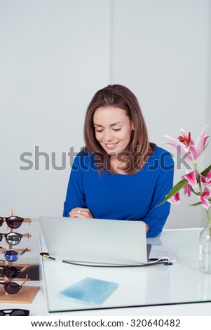 Attractive Young Woman Checking Out a Laptop Computer Inside a Fashion Store with Happy Facial Expression.