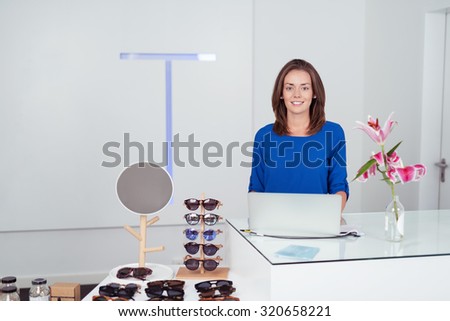 Attractive Woman at the Cashier Counter with Laptop In a Fashion Store, Smiling at the Camera.