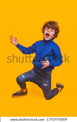 Energetic kid gesturing rock holding guitar