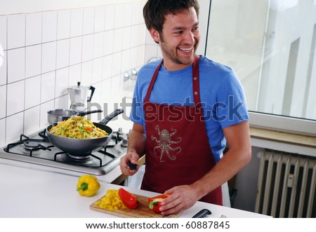 young man stand in the kitchen and cut vegetable