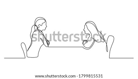 two young women sitting behind table talking