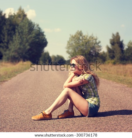 Street Style Fashion Woman Sitting on the Road Outdoors. Toned Instagram Styled Photo with Copy Space. Modern Youth Lifestyle Concept.