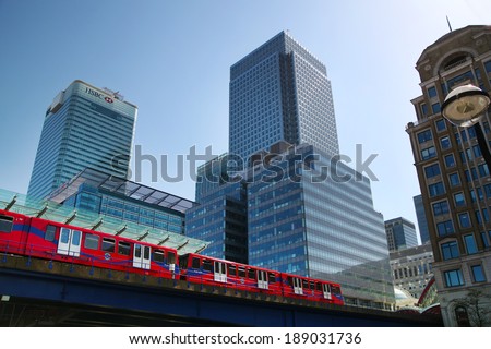 LONDON, CANARY WHARF UK - APRIL 13, 2014: - DLR bridge with train. Modern glass architecture of Canary Wharf business aria, headquarters for banks, insurance, media and other world known companies.