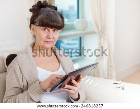 Pension age good looking woman searching in internet on tablet device
