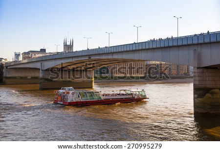 LONDON, UK - APRIL15, 2015: London bridge and tourist\'s boat in sunset light. City of London, south bank Thames river walk.