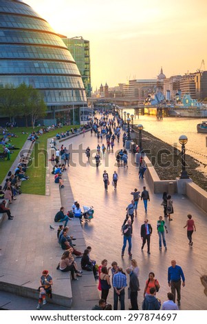 LONDON, UK - APRIL15, 2015: South bank of river Thames in sun set light. View includes a lot of walking people and London hall building