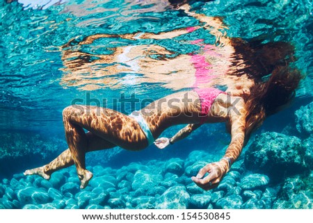 Attractive young woman floating in beautiful ethereal natural ocean pool, Underwater View