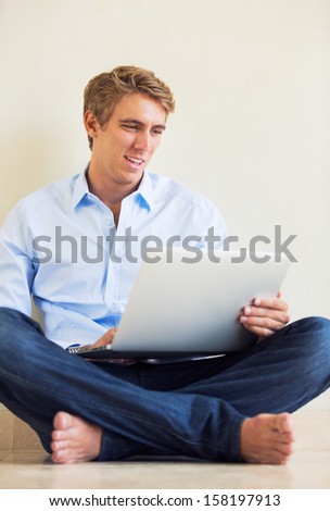 Attractive Young Man Working on Laptop Computer at Home
