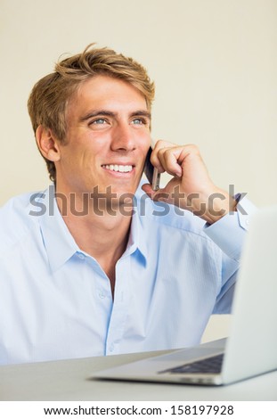 Attractive Young Man Working on Laptop Computer Talking on Phone