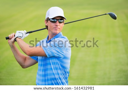 Athletic young man playing golf, golfer hitting fairway shot, swinging club