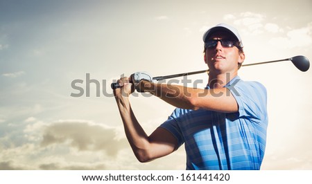 Golfer at sunset, Man swinging golf club with dramatic sunset sky