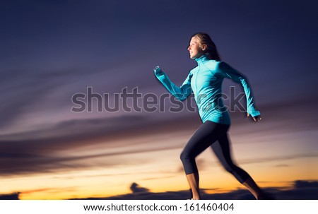 Athletic woman running jogging outside, training outdoors. Running at sunset dusk with motion blur