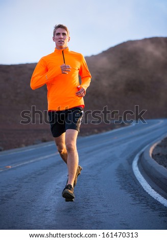 Athletic man jogging outside, training outdoors. Running on road at sunset