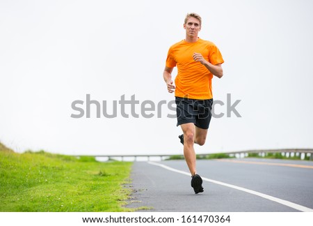 Athletic man running outside, training outdoors. Jogging on road