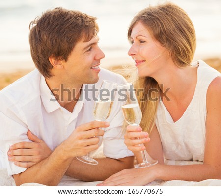 Honeymoon concept, Man and Woman in love, Couple enjoying glass of champagne on tropical beach at sunset