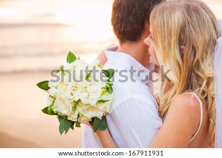 Bride holding bouquet of white flowers gazing at the ocean into the sunset