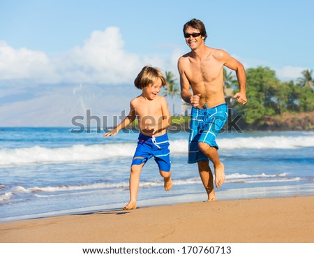 Happy father and son playing and running together at beach, carefree happy fun smiling lifestyle