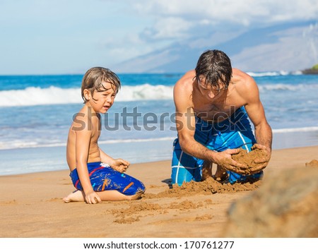 Father and son playing together in the sand on tropical beach, Building sand castle