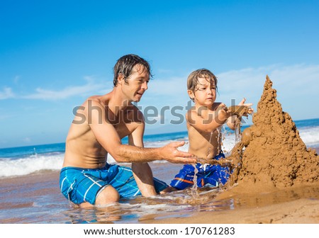 Father and son playing together in the sand on tropical beach, Building sand castle