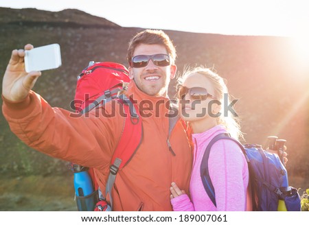 Happy couple taking photo of themselves with smart phone outdoors, Taking a \