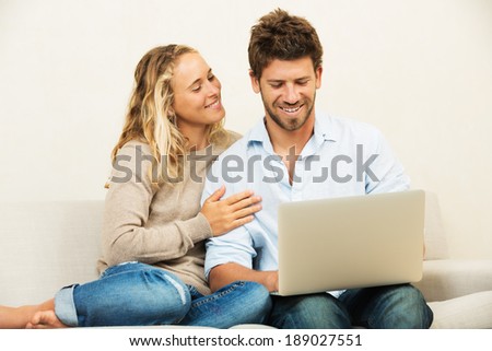 Happy young couple at home using laptop computer