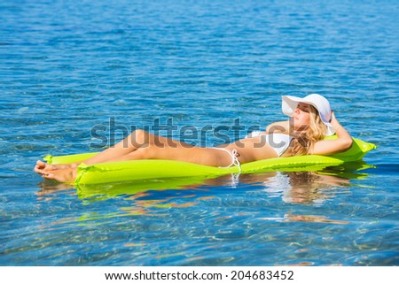 Beautiful woman floating on raft in tropical ocean