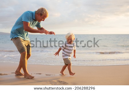 Father and son playing on the beach at sunset