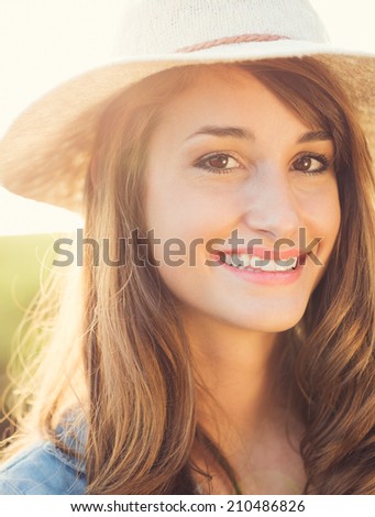 Portrait of a beautiful young woman in hat outside, bright warm sunny color tones