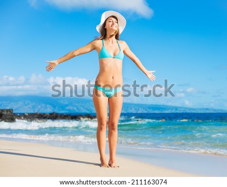 Beach vacation. Beautiful woman in bikini enjoying perfect sunny day at the beach. Open arms, happiness, and bliss.