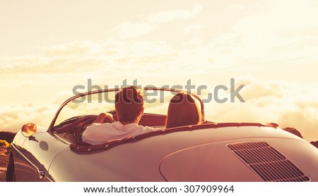 Romantic Young Attractive Couple Watching the Sunset in Classic Vintage Sports Car