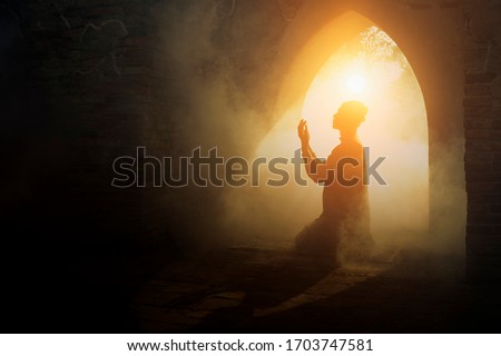 Silhouette of muslim man having worship and praying for fasting and Eid of Islam culture in old mosque with lighting and smoke background                                  