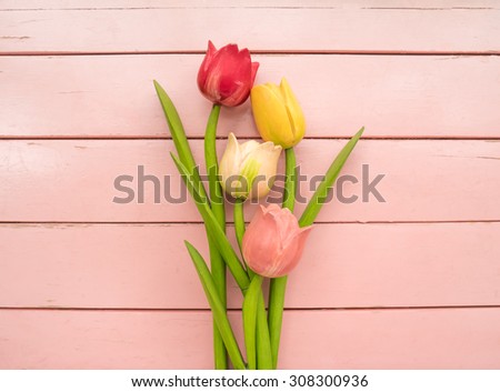 Frame of tulips made of wood arranged on pink wooden background