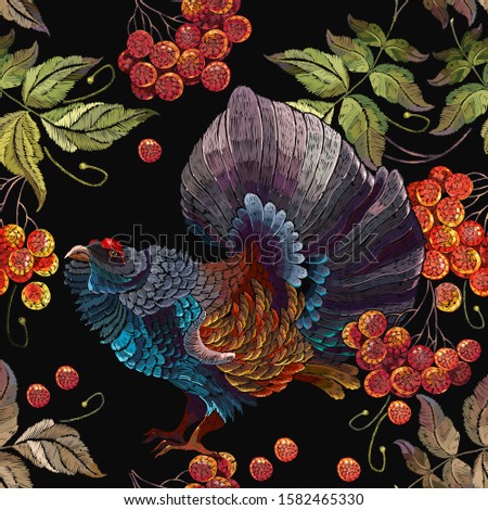 Wood grouse and red branches of a mountain ash berry, seamless pattern. Embroidery art. Western capercaillie (Tetrao urogallus), bird. Wild animals, template for clothes and t-shirt design 