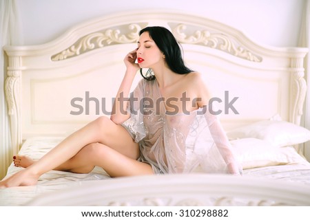 Sexy young brunette woman in sleep dress on sofa .