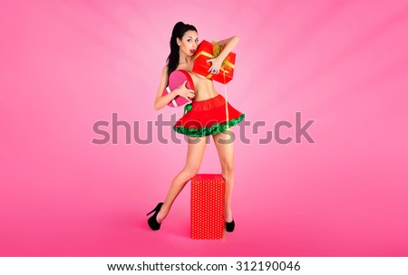 Joyful naked girl in red skirt, having fun emotionally enjoying holding gift boxes on red background.  Valentine day.