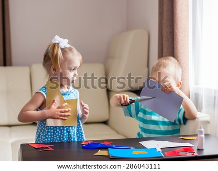 boy and girl are engaged in creative work, cut out of colored cardboard