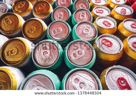 Metal cans of beer with ice cubes in mini refrigerator, close up. Lots of aluminum cans in the ice in the open fridge. Drops of water on a cold can of drink.