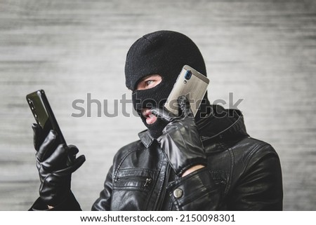 Young adult in black clothes with hidden face. Ill-intended fraudster uses mobile. Fraudster calls. Mobile racket. Hacker hijacks by phone. Cellphone account fraud. Scam Foto d'archivio © 