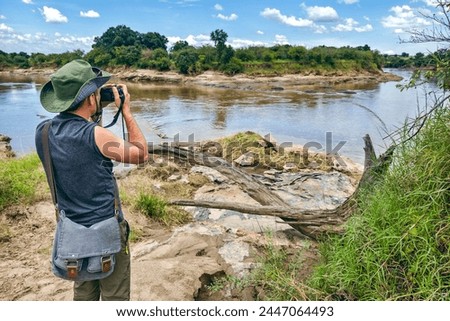 Similar – Image, Stock Photo Male tourist with photo camera standing on rocky lake shore