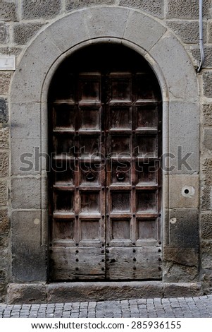old door in the city of Viterbo, italy,\
The door is made of wood and can be seen, especially in the lower part, the ravages of time.