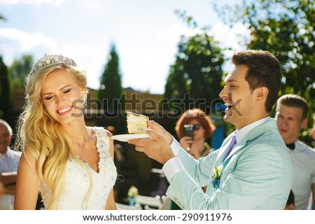 The groom feeds the bride with a piece of wedding cake