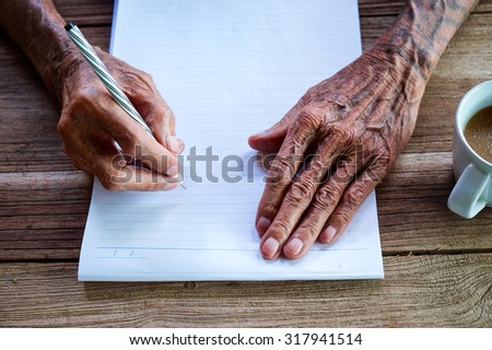 old man writing with a pencil in a notebook,Handwriting