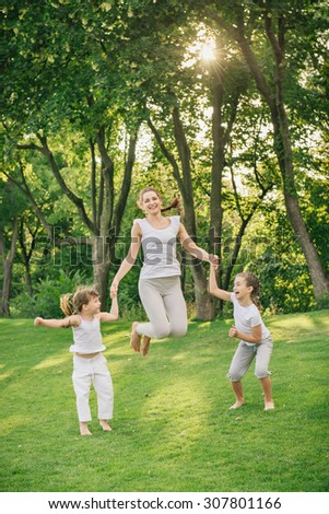 family jumping together at outdoor park against the sun. Happy kids in the same sport clothes as mother.