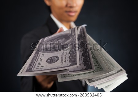 Handsome young man throwing money over dark background