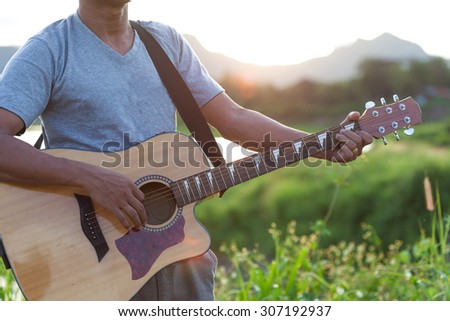 Music hipster youth playing the guitar in park