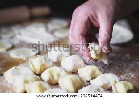 Old woman cooking Ukrainian traditional dumplings with cottage cheese
