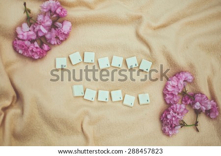 seven and six scrabble squares on the beige cloth background with the sakura blossom in the corners