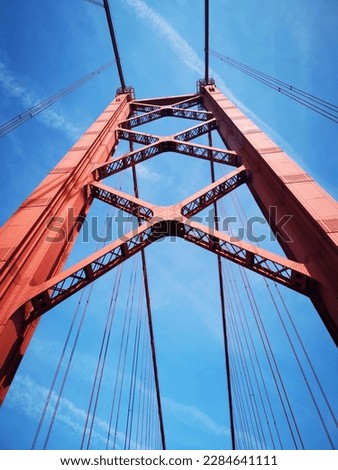 Pillar of the 25 de Abril bridge, the blue sky contrasting with the red of the bridge. Foto stock © 