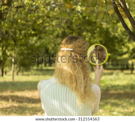 Young beautiful girl look into mirror in the park.Soft and blur conception