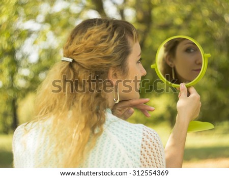 Young beautiful girl look into mirror in the park.Soft and blur conception